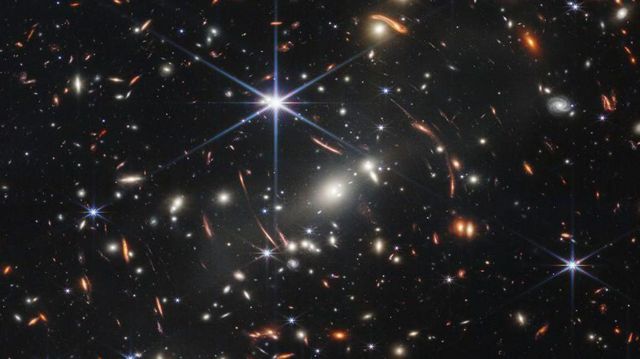 در جلوی این تصویر (جایی نزدیک‌تر به ما) خوشه‌ای از کهکشان‌ها به نام «اس ام اِی سی اس ۰۷۲۳» دیده می‌شود
